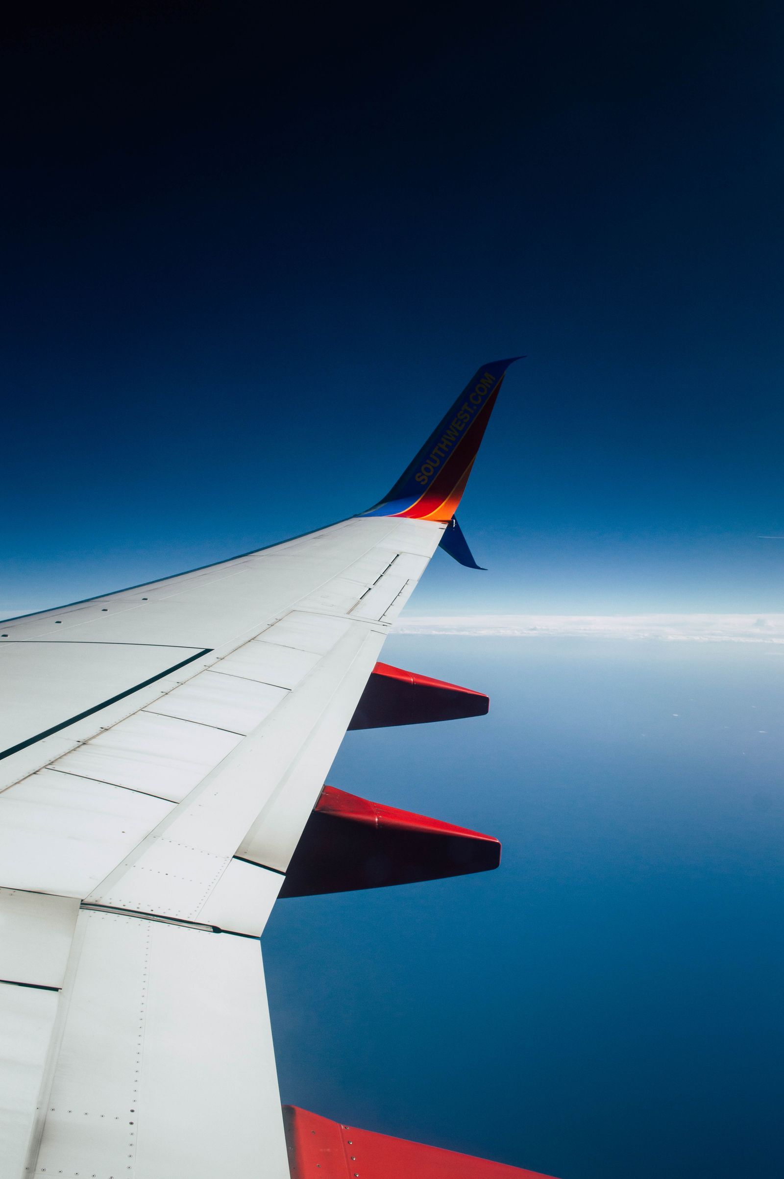 A Southwest airplane wing above the clouds, seen from a passenger window